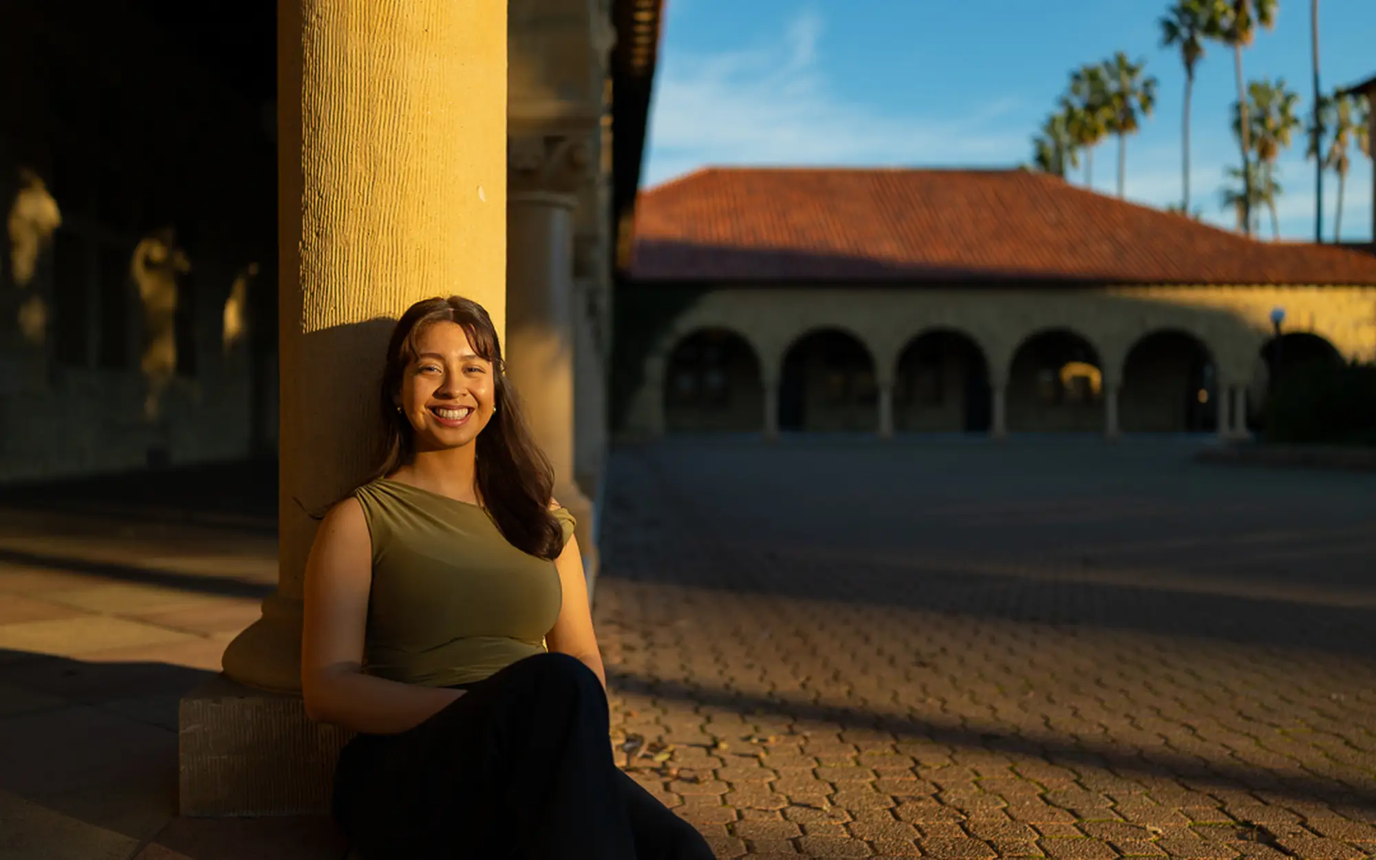 An image of Stephanie Contreras smiling, leaning up against a concrete pillar