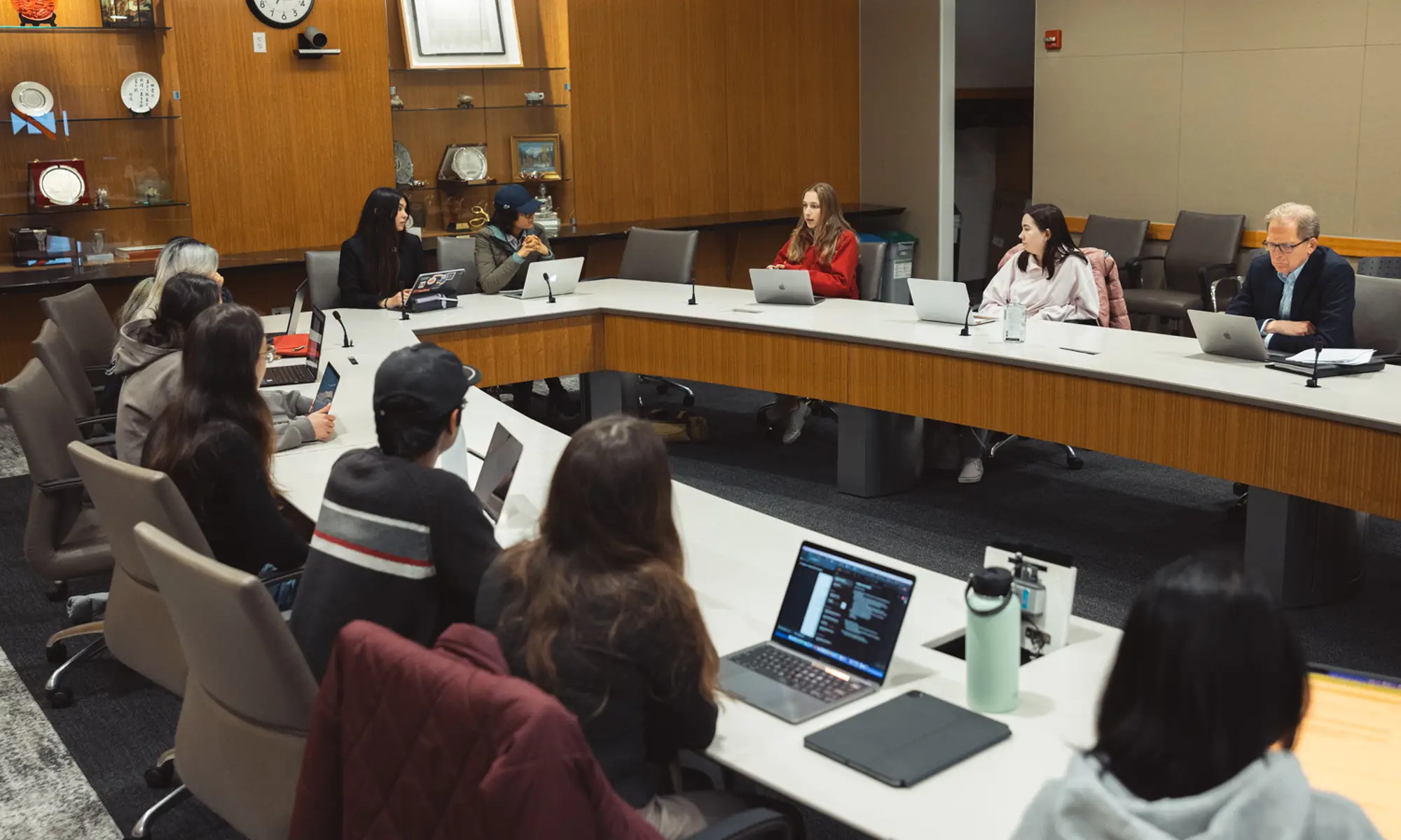 Stanford students with laptops sit at a round table in a classroom