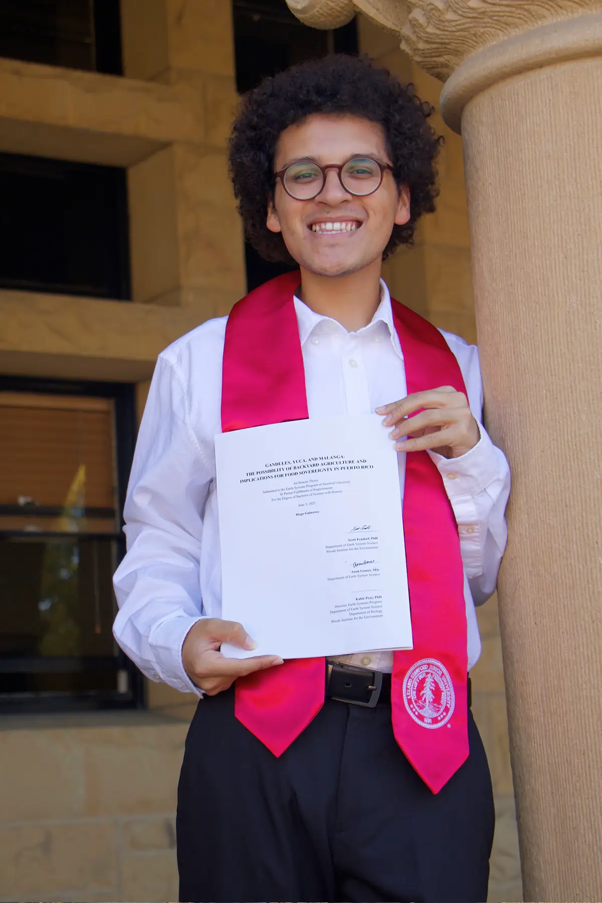 Diego holds his thesis on graduation day