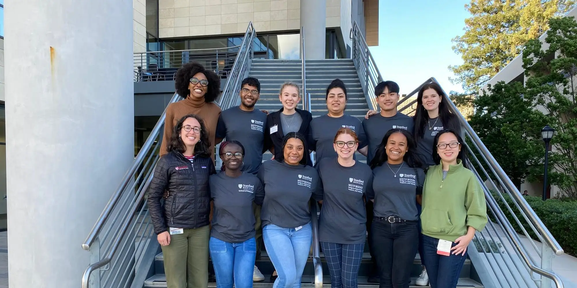 A group of students smile on stairs 
