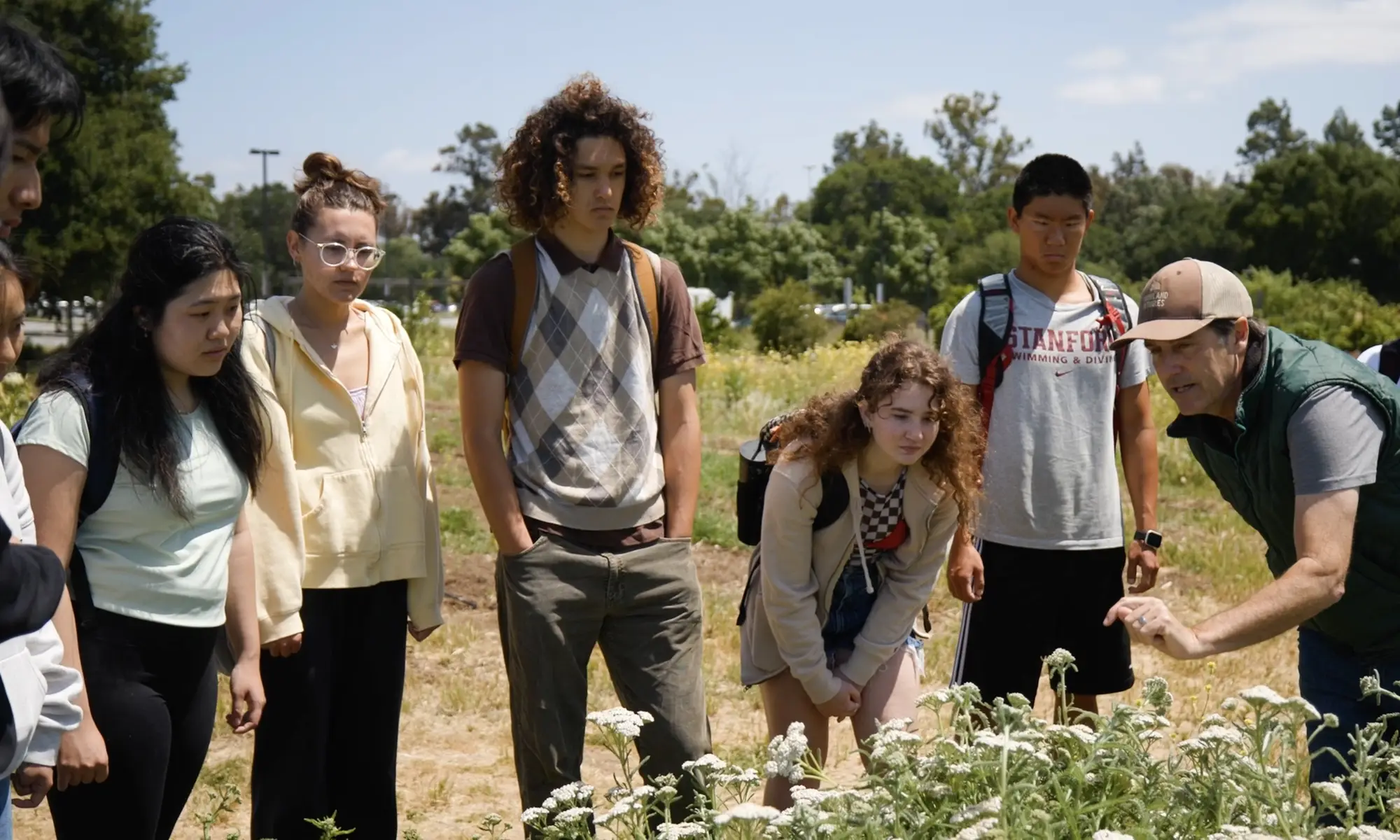 An instructor describes a plant to a group of Stanford students standing together outside
