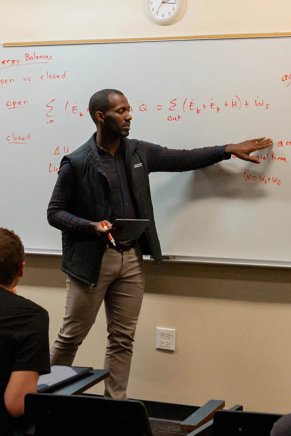 Tarpeh instructing in front of a whiteboard with notes on it.