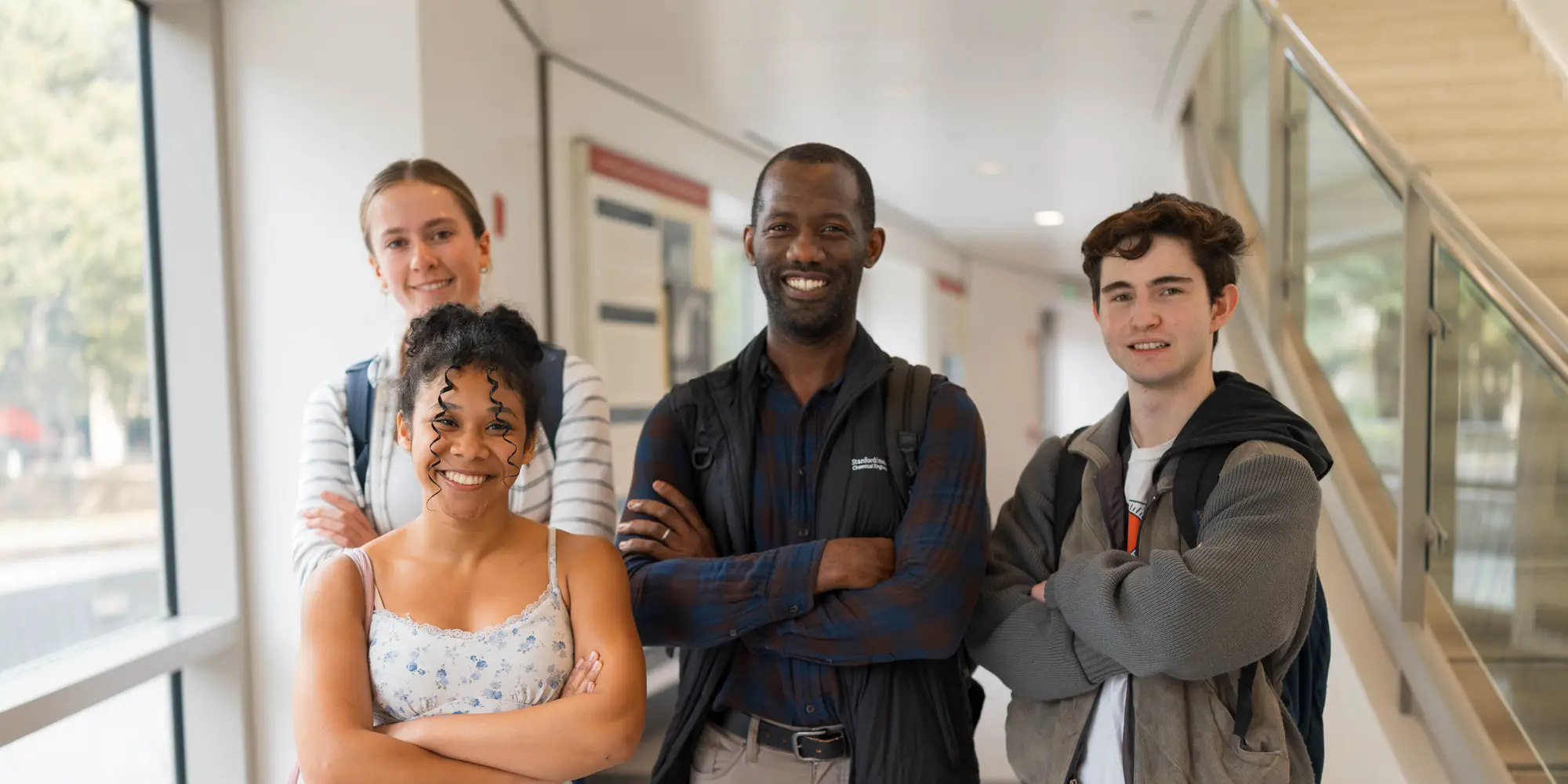 William Tarpeh standing with other students facing the camera. To his right are two female students smiling and to his left is a male student smiling.