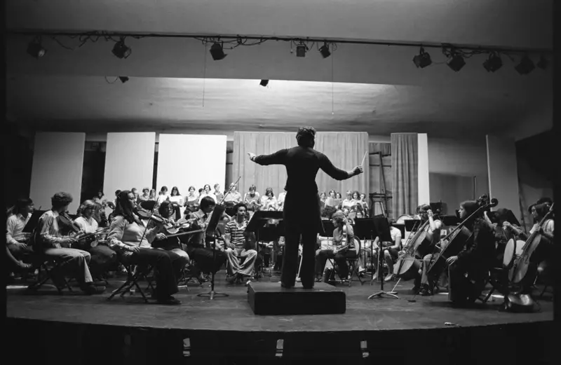 A black and white archival photo of a conductor leading an orchestra