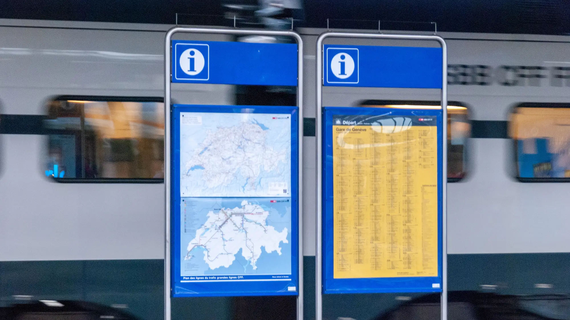 A train passes behind two map signs
