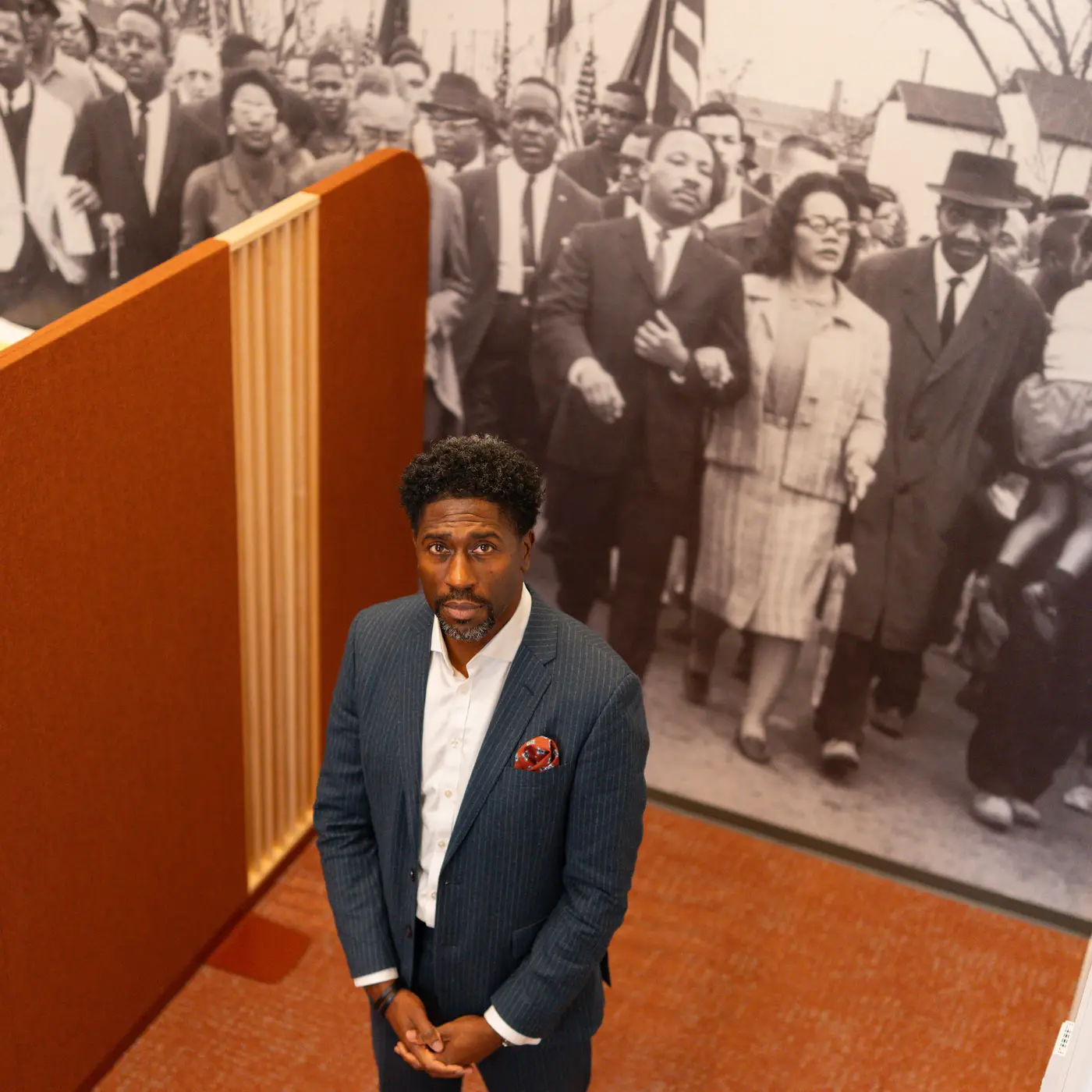 Lerone Martin stands in the MLK Institute in front of a  mural of MLK and his wife at a march.