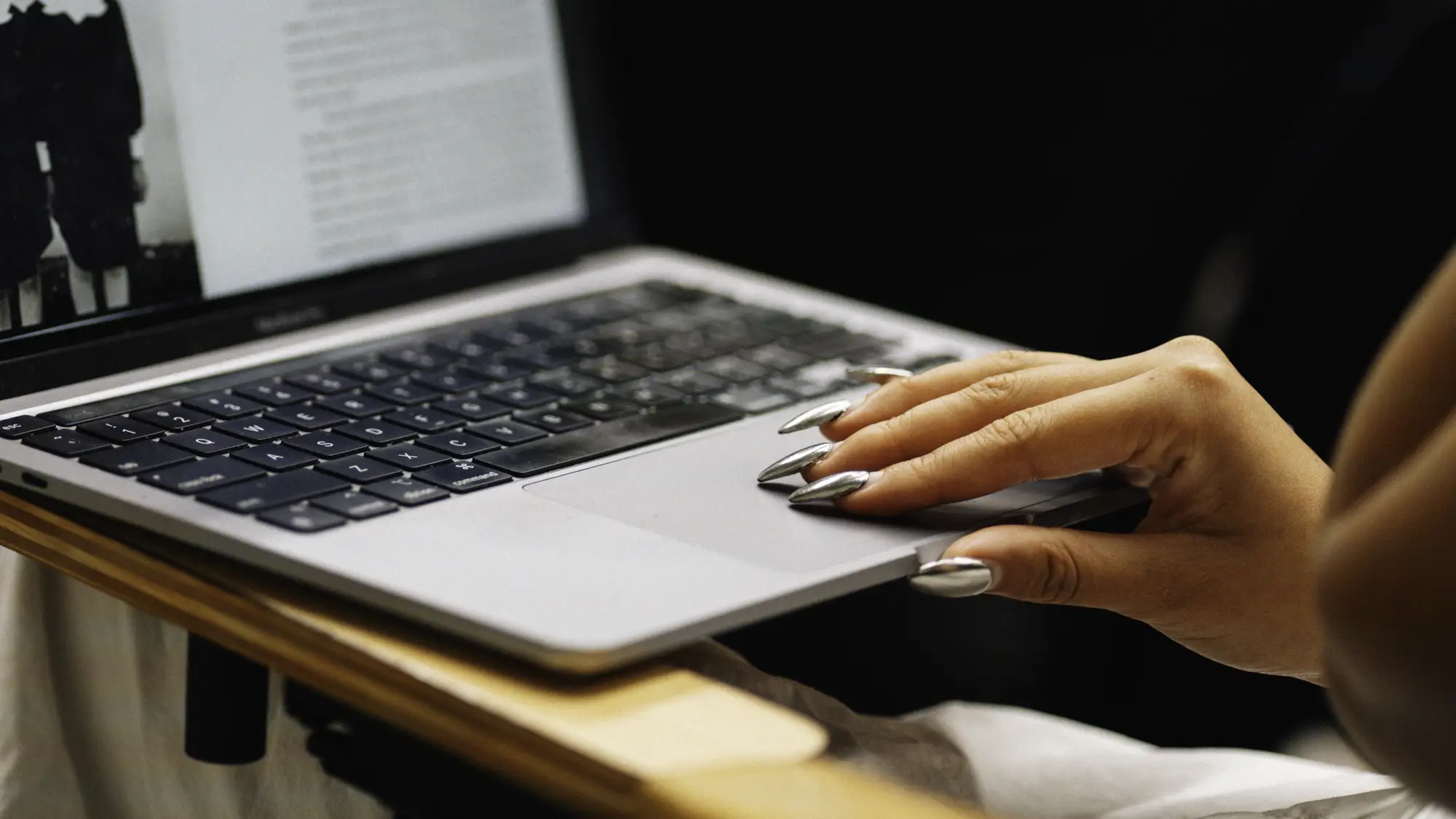 Closeup of a woman's hand on a laptop computer.