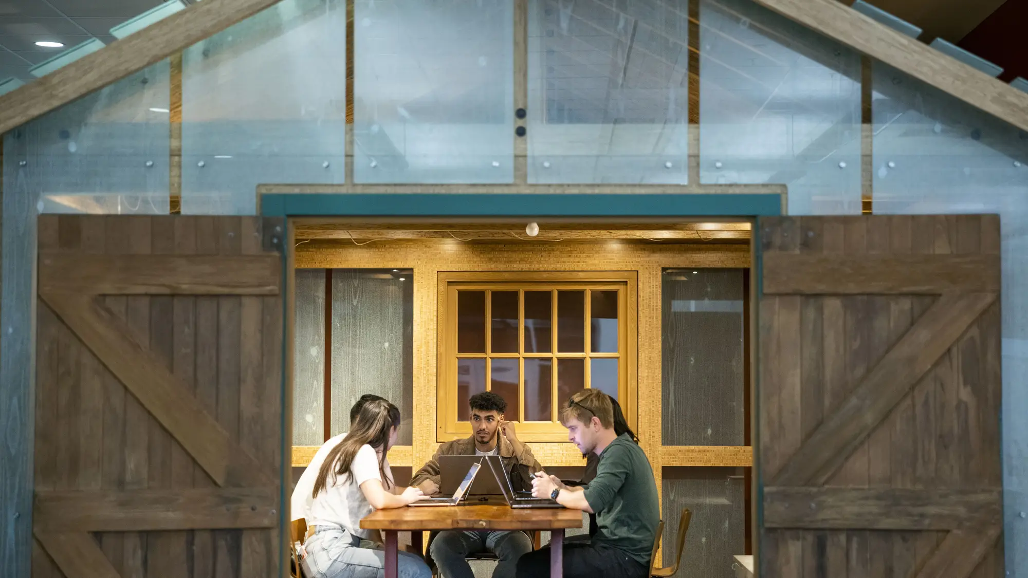 students behind open double doors work together at a table