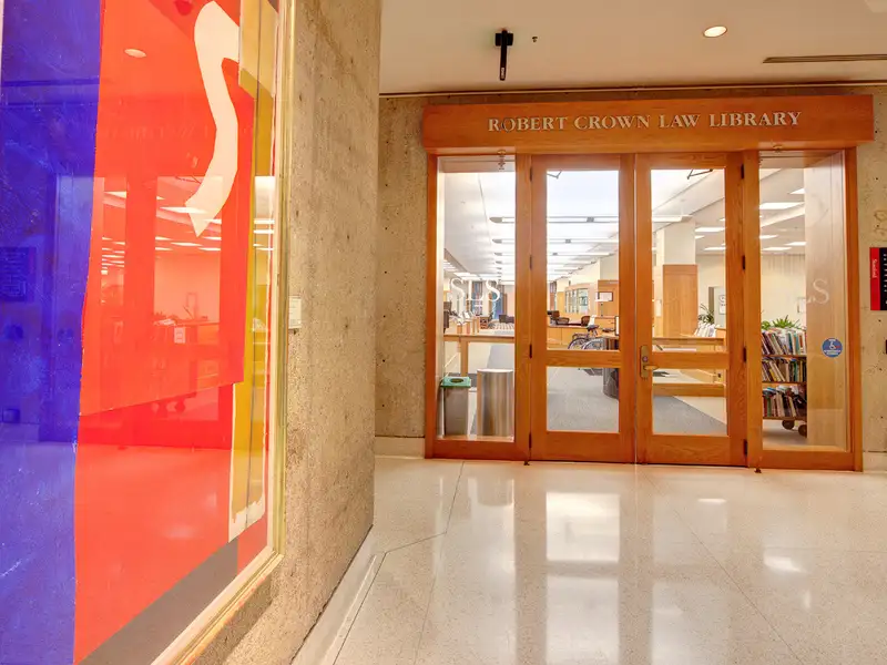 The entrance to the Robert Crown Law Library features wooden doors and colorful artwork on display nearby.