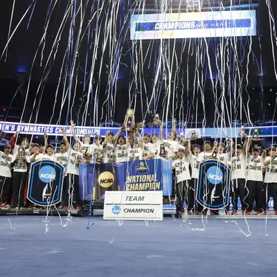 The men's gymnastics team poses for a photo while celebrating their NCAA Championship win.