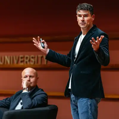 Luke Kemp gestures while presenting at a Stanford University event.