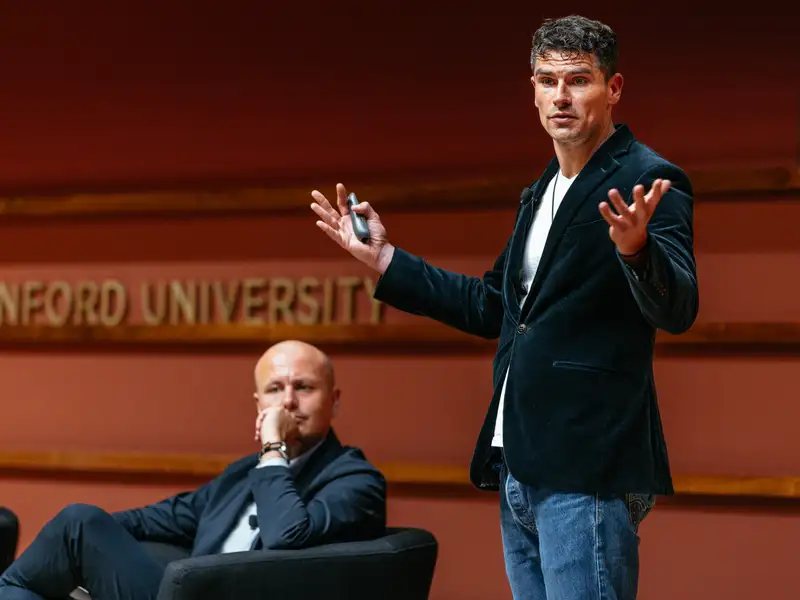 Luke Kemp gestures while presenting at a Stanford University event.
