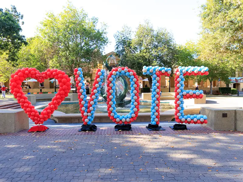 Balloons in the shape or a heart and spell out "vote" in front of Memorial Fountain on the Stanford campus.