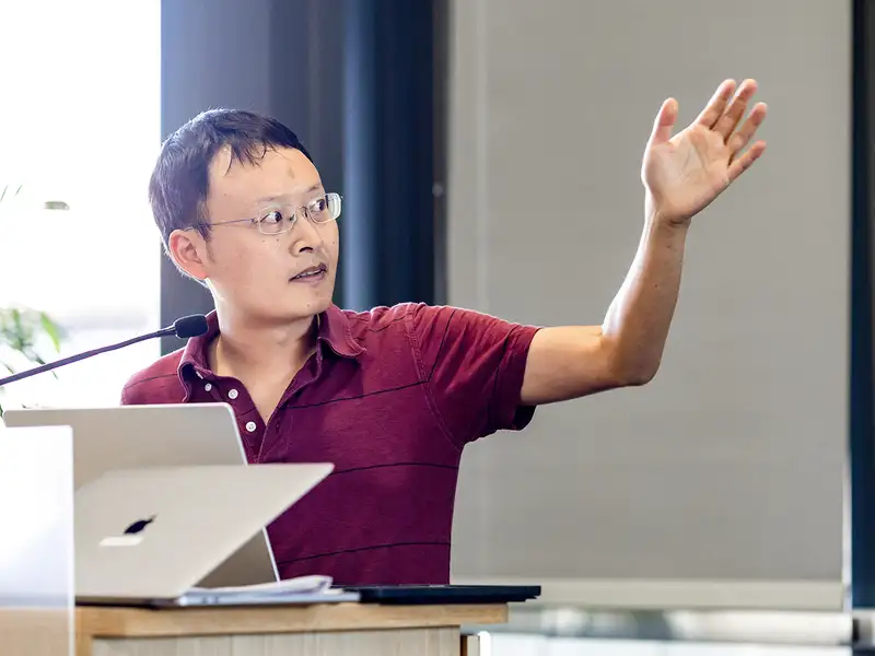 James Zou gestures toward the screen as he gives a talk at Stanford in October 2024.