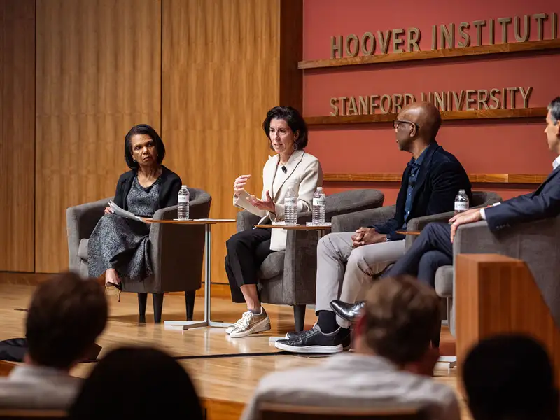 A panel discussion at the Hoover Institution features four speakers engaged in conversation in front of an audience.