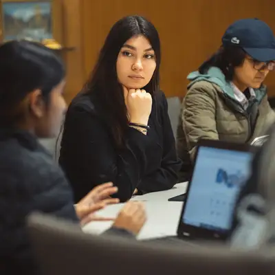 Students seated around a table listen attentively to one another during a discussion period in class.