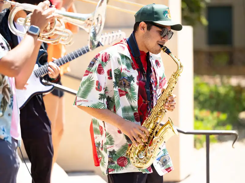 Student playing saxophone in a hawaiian shirt