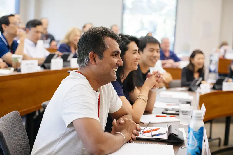 A group of participants attentively listening and engaged during a class or meeting in a conference room setting.
