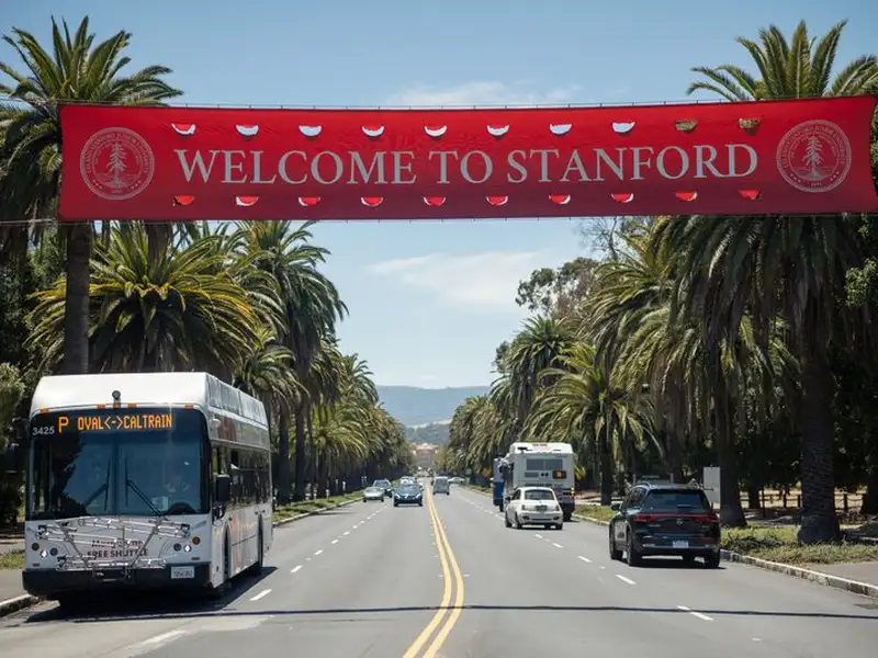 Welcome to Stanford banner over Palm Drive with a shuttle driving under it.