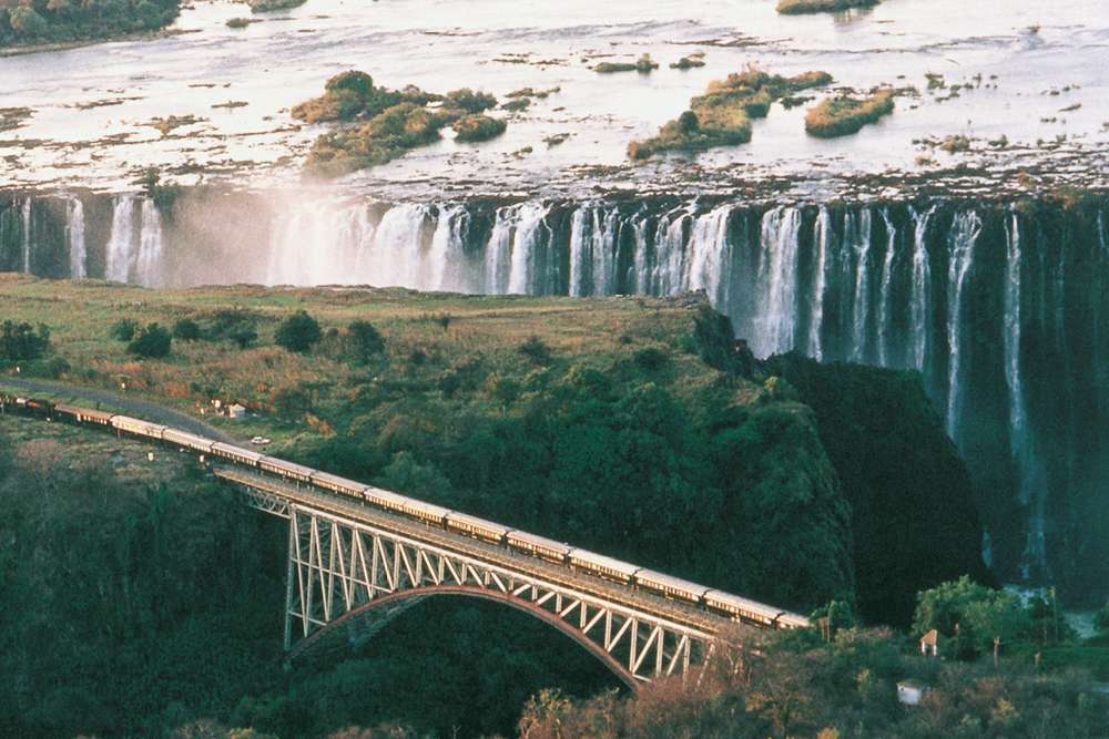 train on bridge near magnificent waterfalls