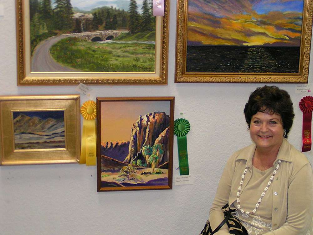 Doni smiles in front of her painting on display