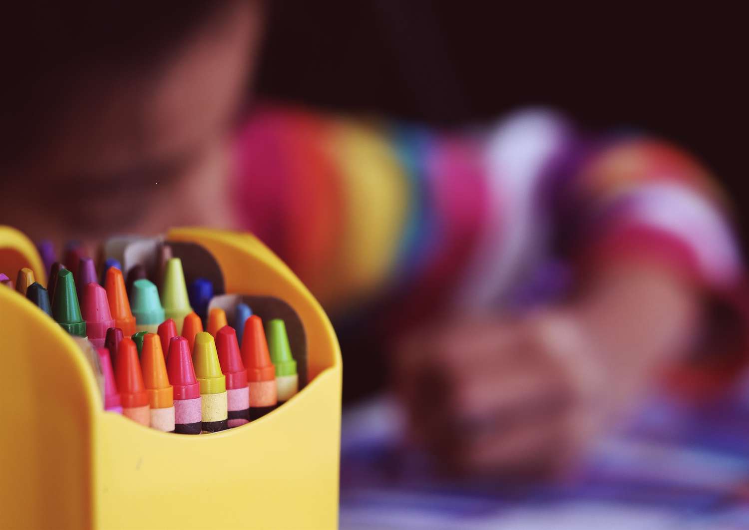 A young child colors with crayons