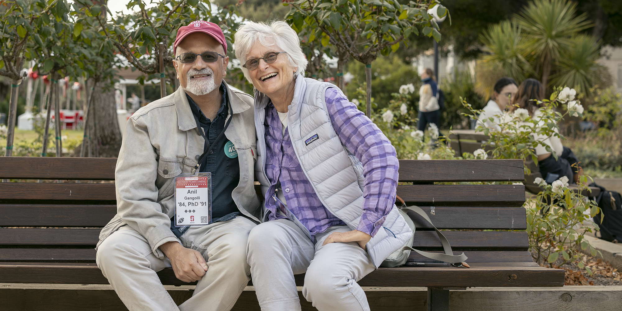 Two alumni smile on a bench