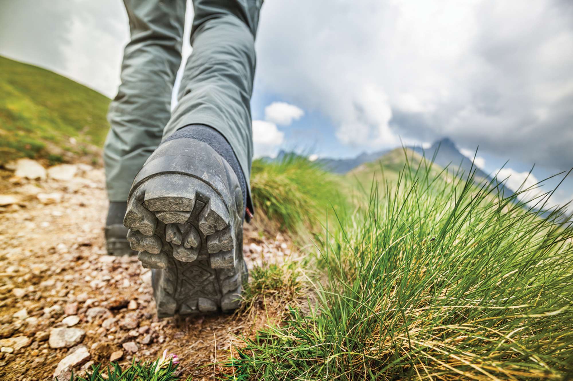 detail showing hiker's boot walking on path