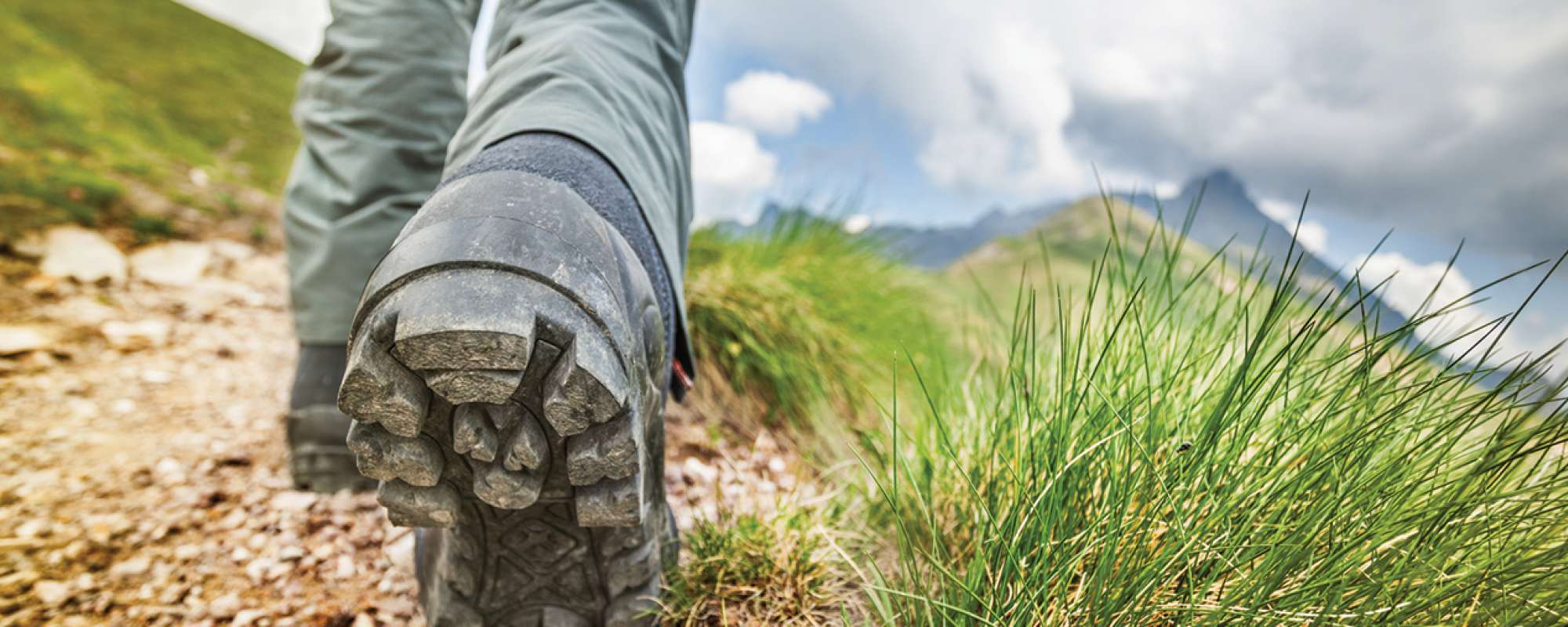 detail showing hiker's boot walking on path
