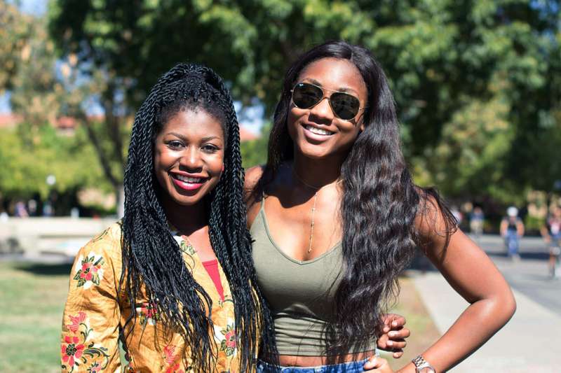Two Stanford students and members of the Nigerian Students Association smile outside on campus