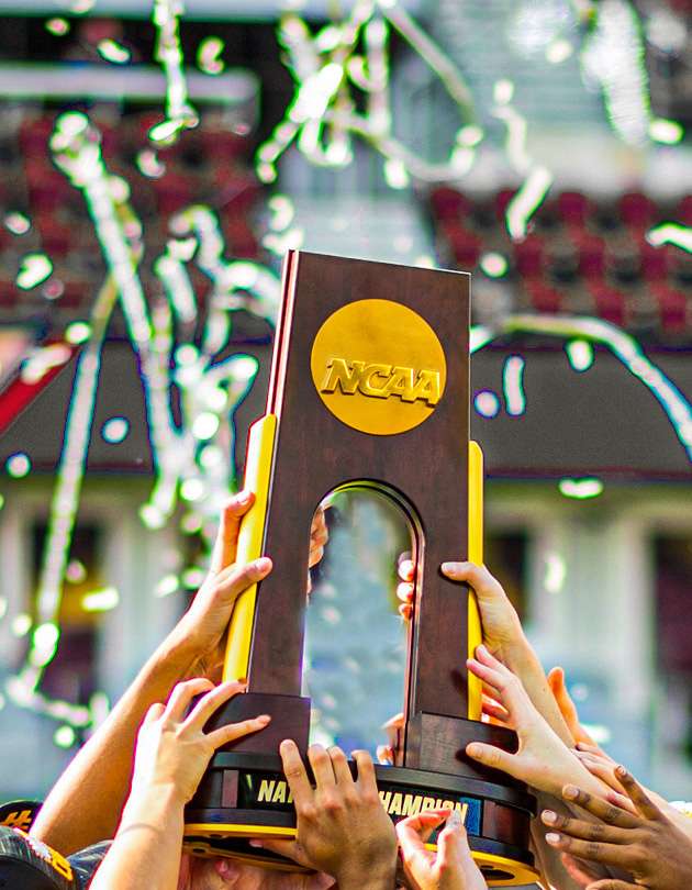 Hands hold up an NCAA trophy